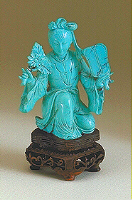 A bright Turquoise, carved as a kneeling lady holding a fan in one hand and a flowering branch in the other.