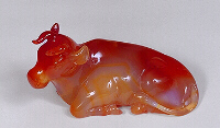 A red and white translucent carnelian carving, with attractive markings, in the form of a reclining cow.