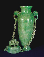 With the cover off: A double chained celadon green jadeite vase and cover. With dragon's head handles suspending loose rings to which each chain having ten loose double links are attached to the cover. Well hollowed, and splashes of emerald green well used to carve dragons in high relief.