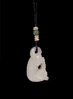 Nephrite pendant, mutton fat, carved in the form of a reclining dog with one rear paw in its mouth, its tail looped over onto its back to form the suspension area for the pendant.