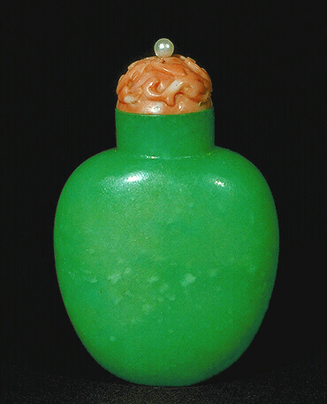 A plain apple green jadeite snuff bottle, well hollowed with a coral carved with a dragon and pearl finial. 