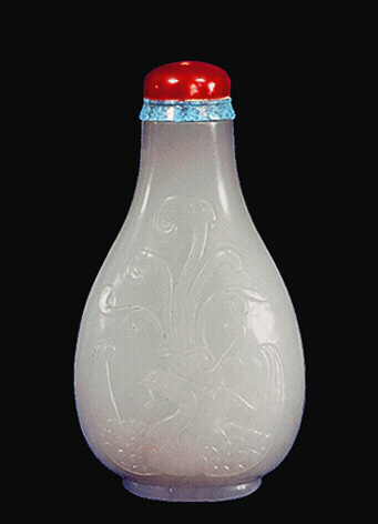 A white nephrite snuff bottle, well hollowed, carved in low relief with a dragon and a phoenix, red coral and turquoise stopper. (Can see the snuff inside).