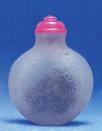 Translucent quartz snuff bottle and carved in low relief with dragons. Pink glass stopper. 