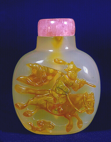 Chalcedony snuff bottle, pale grey with a russet brown skin exceptionally well carved to depict a mounted bannerman in full ceremonial regalia, galloping with his banner flowing behind him, with a tourmaline stopper.