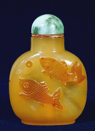 Chalcedony Snuff Bottle, dark honey with a russet translucent skin carved with two fish and a bubble, a third fish on the reverse, with lotus and millet.