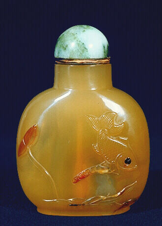 Reverse of the Chalcedony Snuff Bottle, dark honey with a russet translucent skin carved with two fish and a bubble, a third fish on the reverse, with lotus and millet.