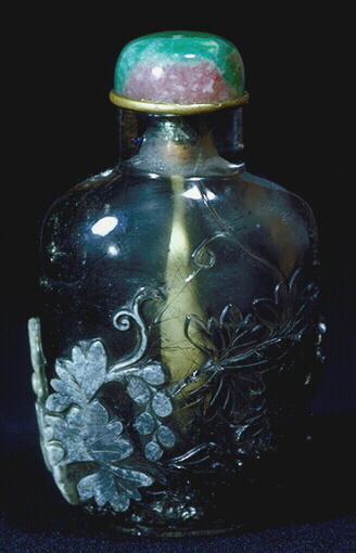 Reverse: Quartz, hair crystal snuff bottle, with tourmaline needles of varying densities and a mottled opaque creamy white inclusion carved to depict a squirrel below a grape-laden vine.