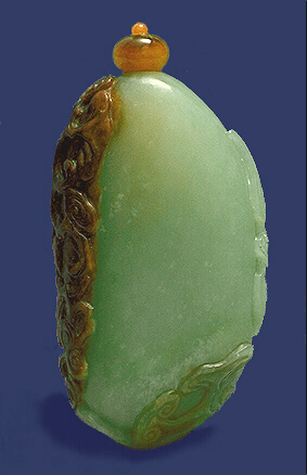 Nephrite snuff bottle, white with an ochre and brown skin, the brown area carved with lotus leaves and a lingzhi fungus, and above that on the lighter material is a bat in flight; the well hollowed bottle of natural pebble form.