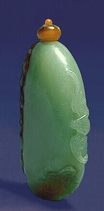 Side View: Nephrite snuff bottle, white with an ochre and brown skin, the brown area carved with lotus leaves and a lingzhi fungus, and above that on the lighter material is a bat in flight; the well hollowed bottle of natural pebble form.