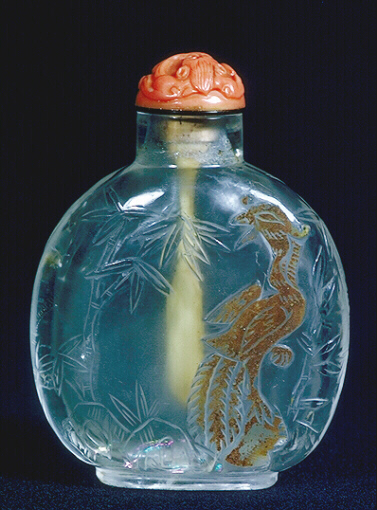 Quartz, crystal cameo carved snuff bottle , the clear, colourless material with a thin brown skin, sensitively carved with a phoenix looking back over its shoulders towards bamboo growing from the rocks below.