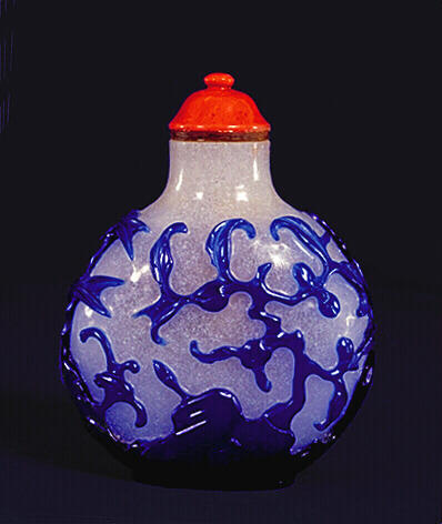 The reverse of the snowflake ground glass snuff bottle with a sapphire-blue overlay carved with bats flying amongst clouds above turbulent waters.