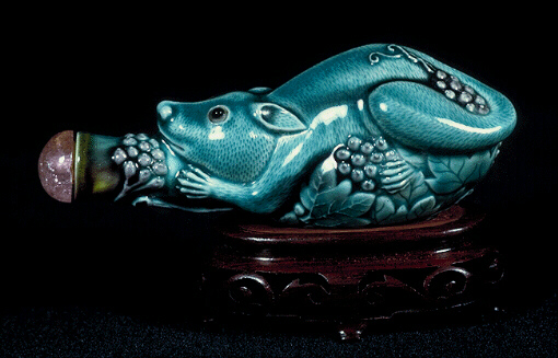 Porcelain snuff bottle, covered in a turquoise glaze and molded in the form of a squirrel gripping onto a branch from which cascade grapes and vine leaves; the leaves, fur and facial expression superbly molded.