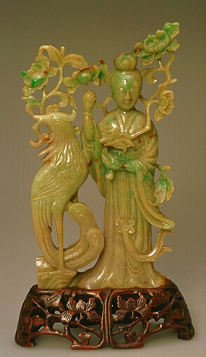 A Celadon and russet jadeite carving of Guanyin with phoenix and flowers.