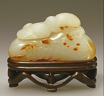 The reverse of the fine handling piece of white jade with some russet markings. When viewed by turning this piece around, and upside down, a number of images can be discovered:- lingzhi, pair of quail on rocks, an old prunus tree, a dragon on a rock, and a mandarin duck.