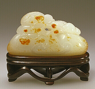 A fine handling piece of white jade with some russet markings. When viewed by turning this piece around, and upside down, a number of images can be discovered:- lingzhi, pair of quail on rocks, an old prunus tree, a dragon on a rock, and a mandarin duck.