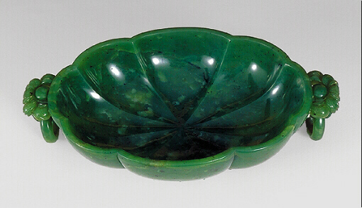 Showing the inside: An even spinage green nephrite bowl, with black flecks, carved as a bowl with loose ring handles and a chrysanthemum style base.