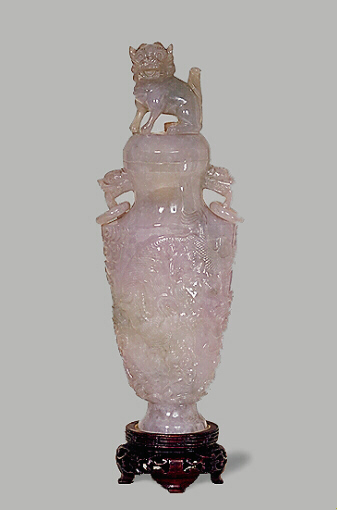 A carved Jadeite lavender vase, with loose ring handles, decorated in relief with a continuous design of dragon and clouds. The cover carved as a dog of fo.