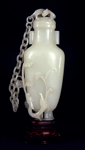 A pure white nephrite chained vase, well hollowed, of an archaic bronze shape with a curled dragon on the cover. Another dragon with flowering prunus to which the (twenty section) chain links to the cover. 