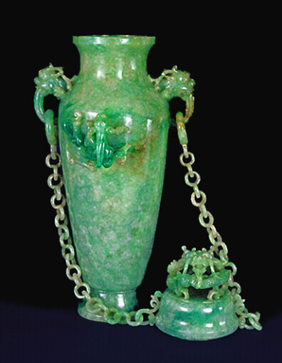 With the cover off: A double chained celadon green jadeite vase and cover. With dragon's head handles suspending loose rings to which each chain having ten loose double links are attached to the cover. Well hollowed, and splashes of emerald green well used to carve dragons in high relief.