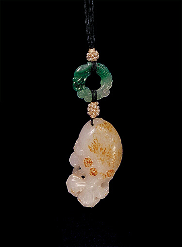 Nephrite pendant, mutton fat with mottled russet skin carved as a plump fish with a spray of lotus in its mouth. A bright green jadeite ring in the form of a dragon biting its tail.