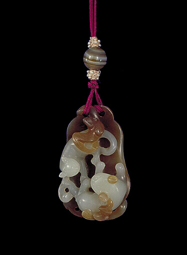 Nephrite pendant, white mutton fat with darker brown olive skin, the white carved with a mother cat and younger cat playing together, resting on an artemis leaf.