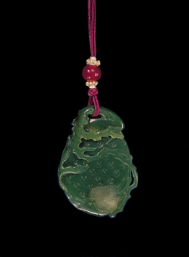 Nephrite pendant, spinach colour, carved as a lychee fruit the paler green areas carved as a flowering prunus, above is the gnarled tree trunk and to the side is a small iris bud.