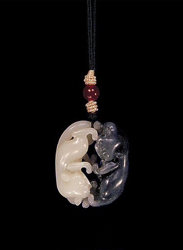 Nephrite pendant, mutton fat white with dark grey areas cleverly carved with two cats playing, the two cats carved precisely from the two colours.