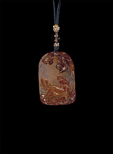 Chalcedony pendant, pale translucent colour with darker brown skin, carved as a kylin with ruyi fungus and clouds above. The reverse with a rocky cavernous area and a raised inscription to one side. Suzhou School.