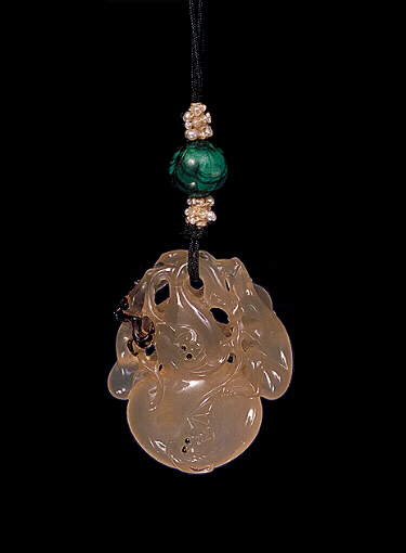 Reverse: Chalcedony pendant, pale translucent beige carved as a double gourd covered with bats, on the other side a monkey and an iris plant and a bat. All the bats and the monkey's eyes are carved out of a darker inclusion.