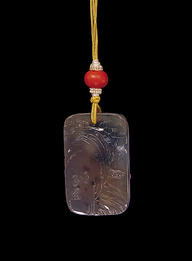 Reverse: Chalcedony pendant, pale translucent stone with a darker brown skin, carved with a monkey scampering amongst the pine with a rockery below. The other side with craggy rockwork, pine and clouds and a raised inscription. Suzhou School.