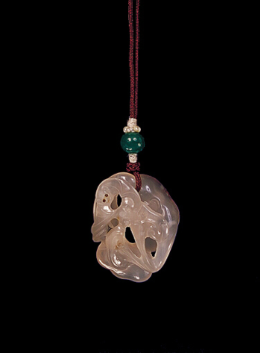 Reverse: Chalcedony pendant, pale translucent stone with a darker brown skin carved as the eyes of a bat amongst ruyi fungus. The reverse with a long raised inscription from the brown skin.