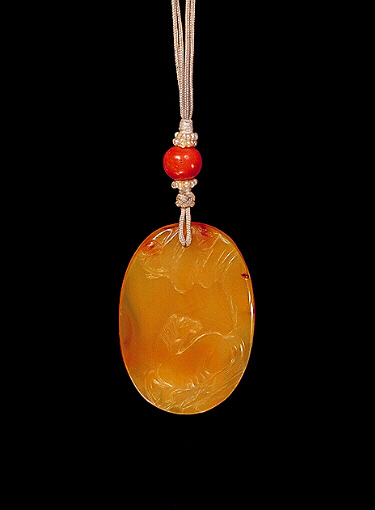 Chalcedony pendant, pale translucent, orange agate carved with a reclining horse on a rocky landscape, the other side with a monkey down amongst rocks and water looking up at tempting peaches. Suzhou School.