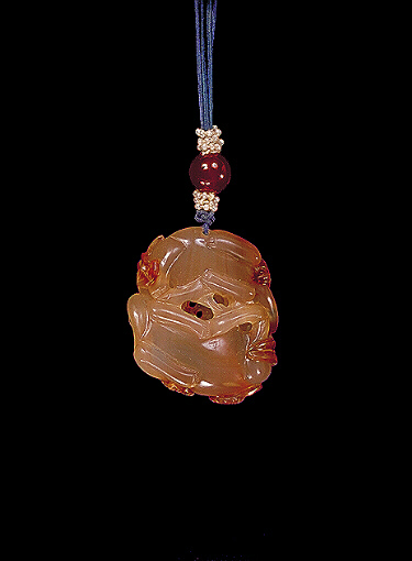 Reverse: Chalcedony pendant, pale translucent orange agate with much darker russet areas carved with two feline animals curled up together with chrysanthemum flowers with leaves entwined around.