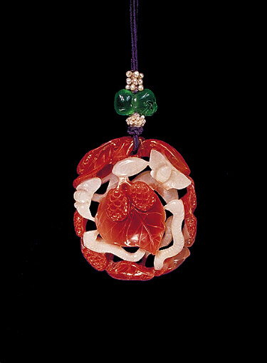 Carnelian pendant, pale creamy white with bright, orange veins, the central white area carved with moths and silk worms, centring around mulberry leaves and fruit, the outside carved with leaves and mulberry fruit.