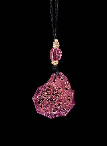 Pink tourmaline pendant, carved in an irregular form with the outline of bamboo surrounding peach sprays and branches.