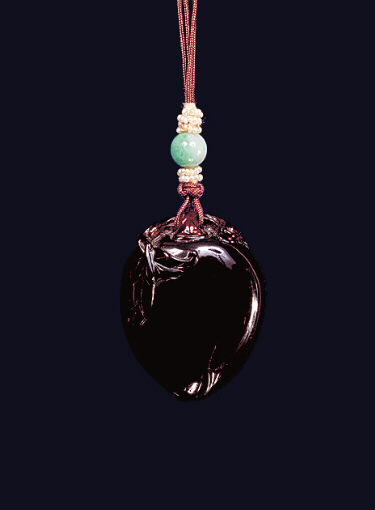 Amber pendant of dark toffee colour carved in the form of a perfect peach, its leaves around the top.