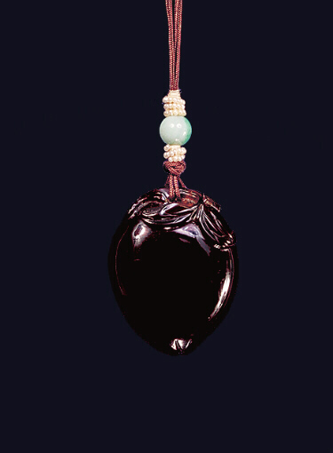 Reverse: Amber pendant of dark toffee colour carved in the form of a perfect peach, its leaves around the top.