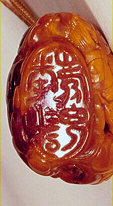 Seal: Amber pendant, of dark translucent golden colour with opaque paler material carved with a tiger from the translucent material and a dragon amongst clouds from the opaque material, the foot carved with a personal seal.