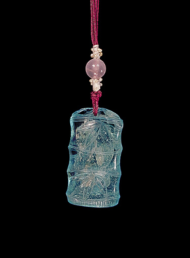 Reverse: Glass pendant of pale translucent blue, suffused throughout with lighter creamier areas in imitation of aquamarine, the body carved as a section of bamboo with leaves.